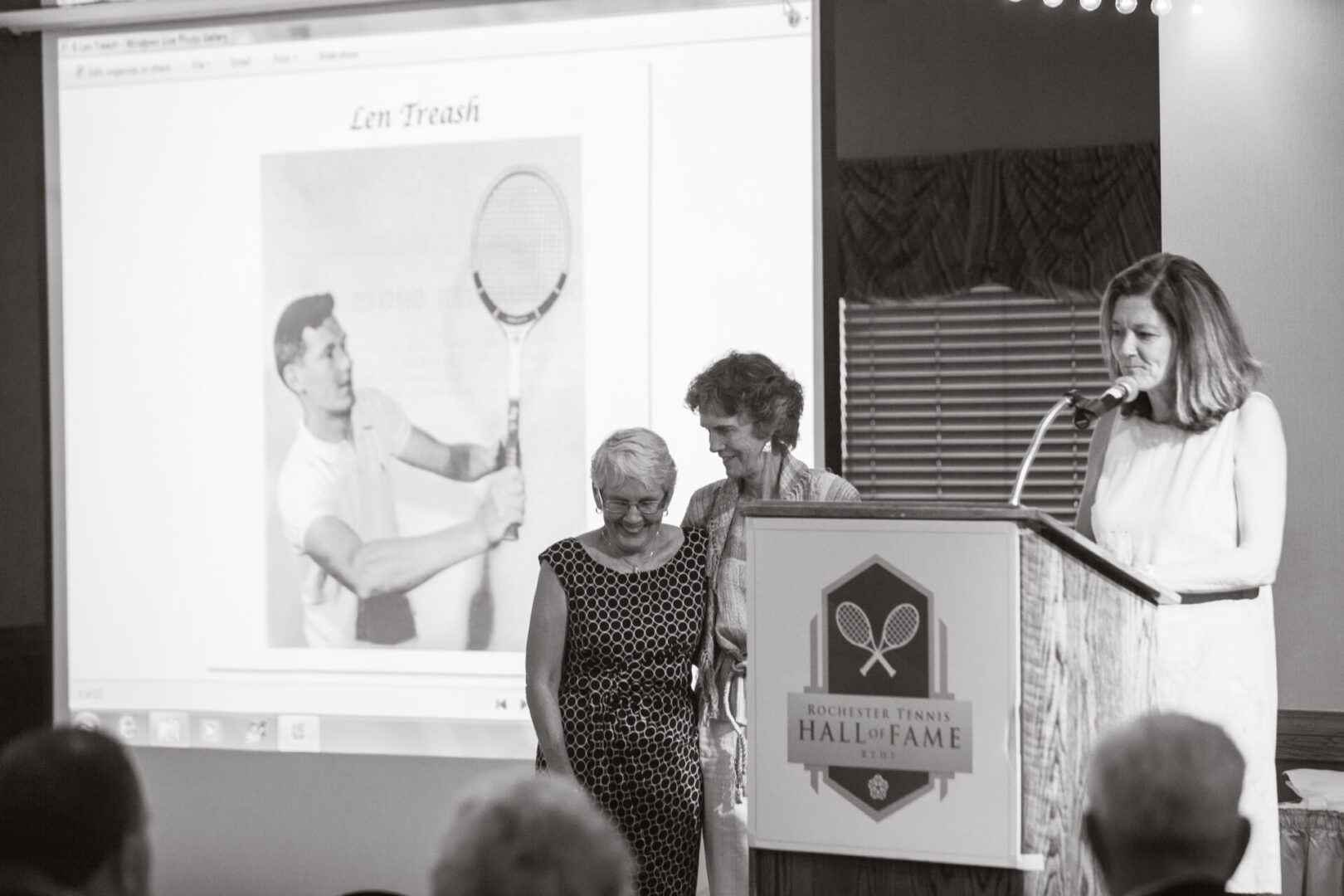 Two people standing at a podium with a tennis racket.