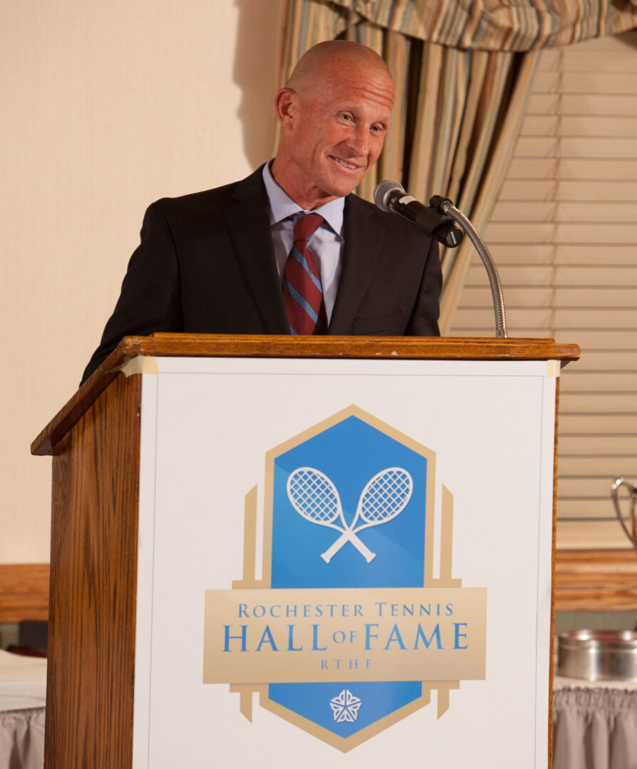 A man in suit and tie standing at the podium.