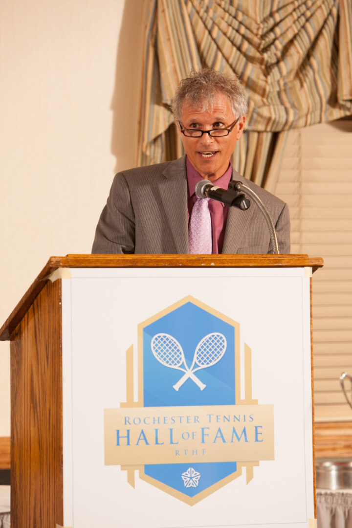 A man in suit and tie standing at a podium.