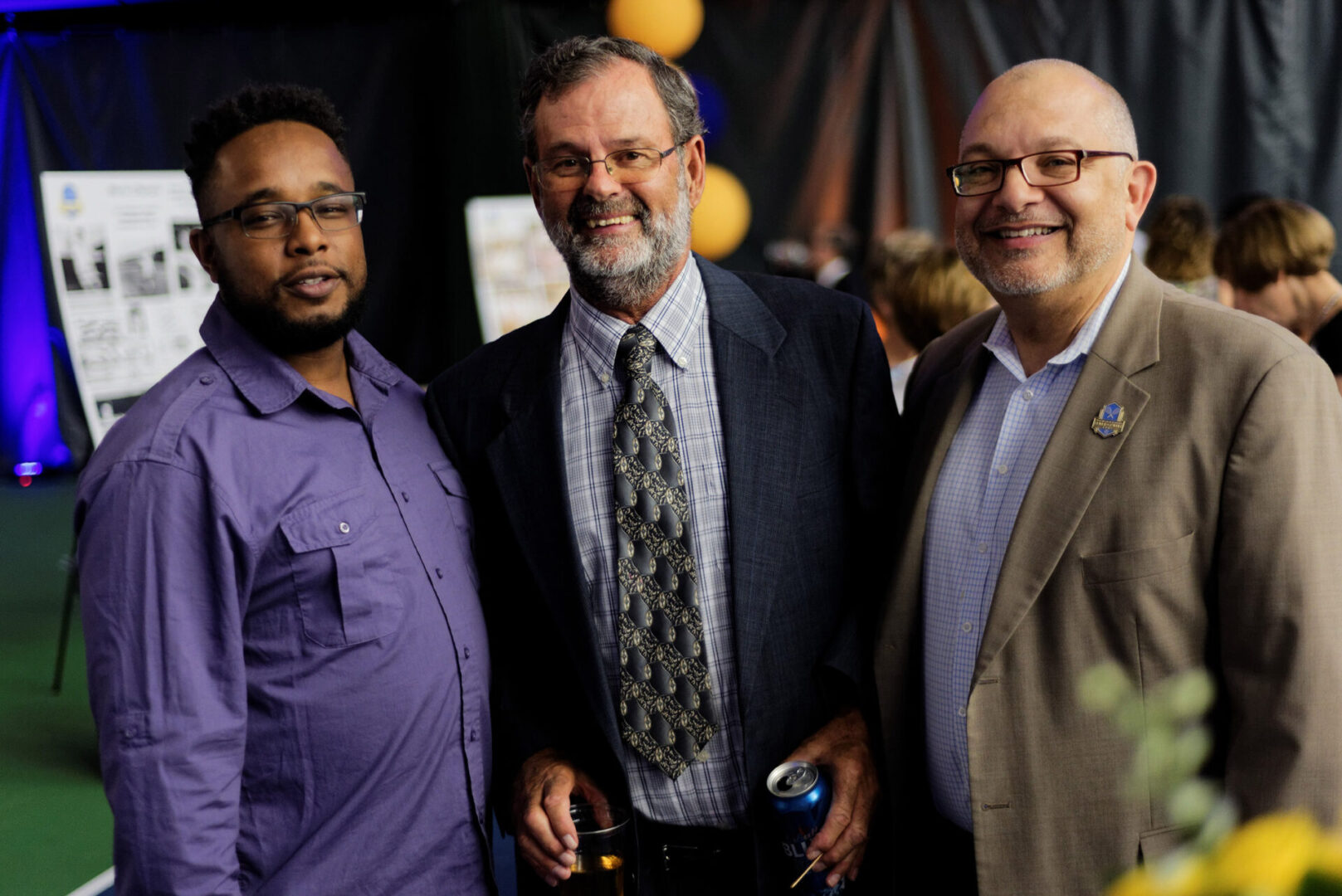 Three men standing next to each other at a party.