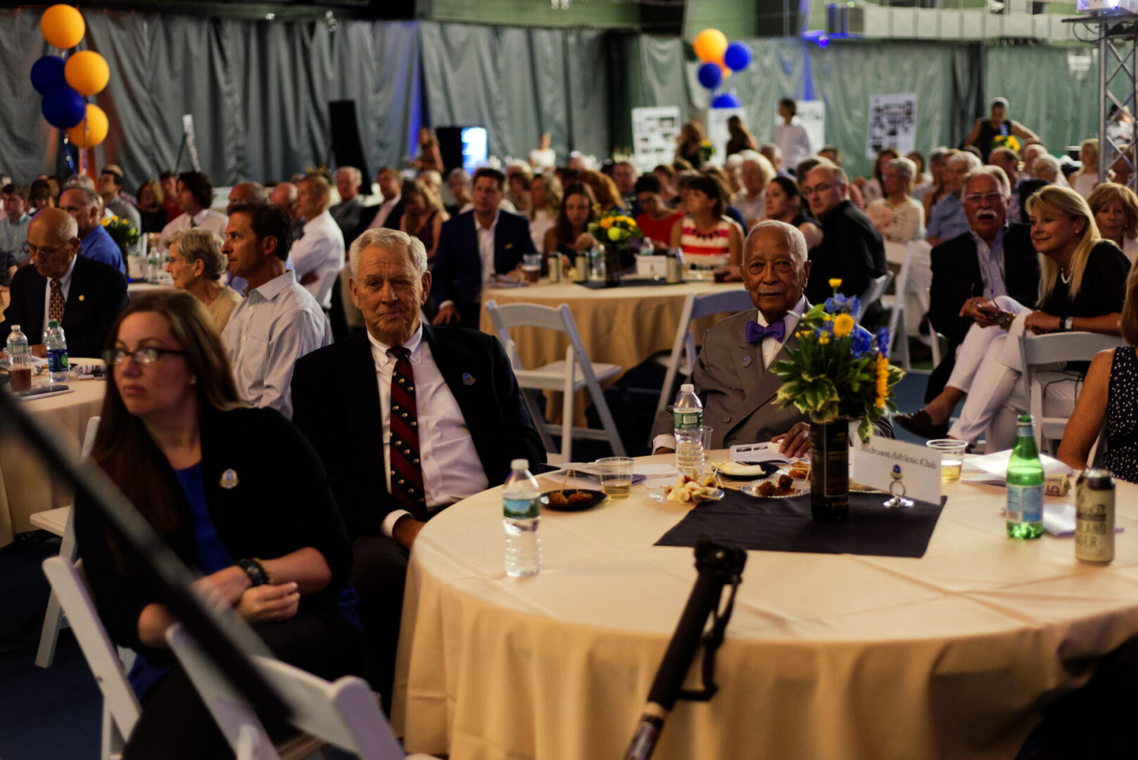 A group of people sitting at tables with balloons.