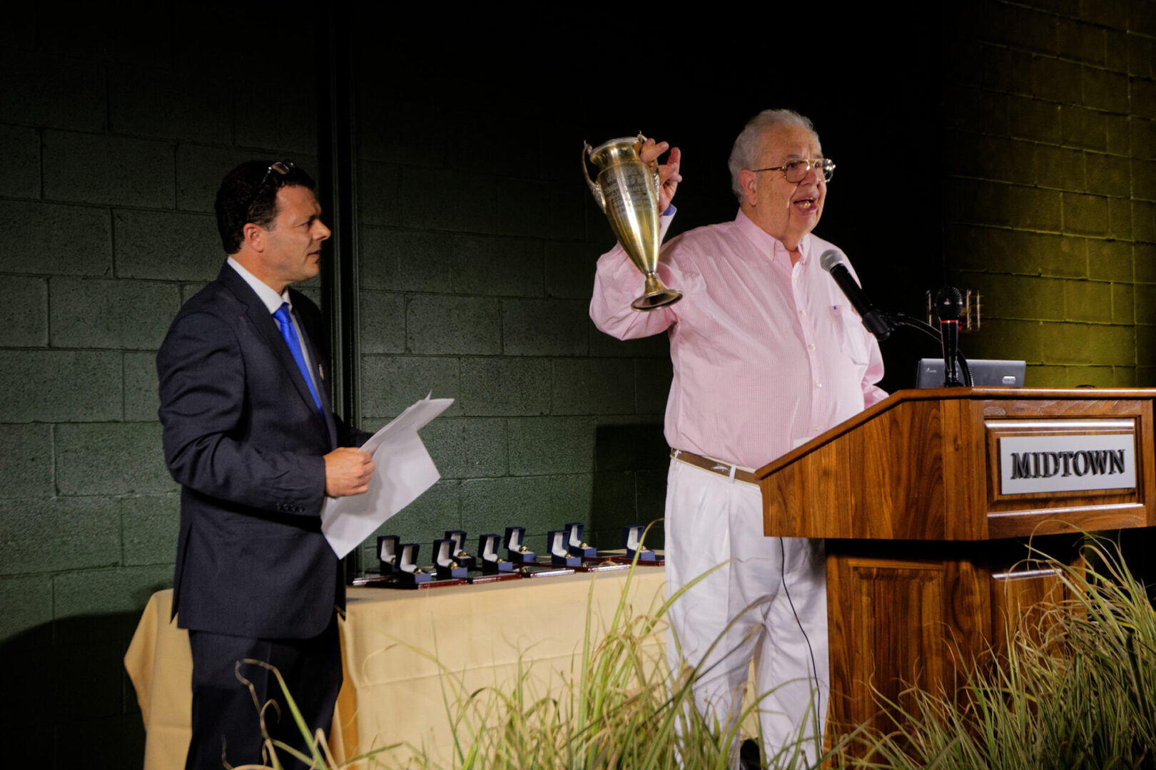 A man holding up a trophy while standing at a podium.