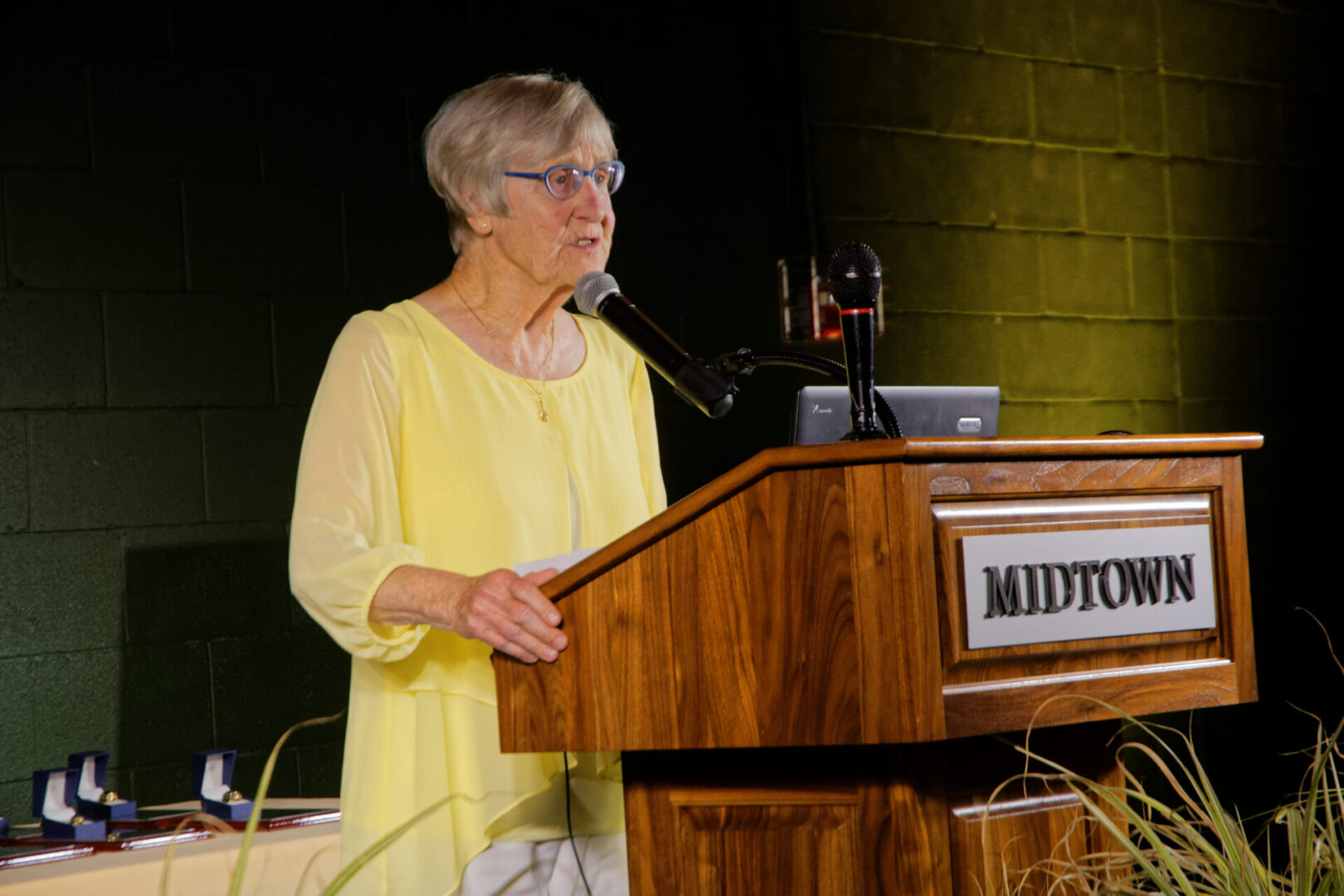 A woman in yellow is speaking at the podium