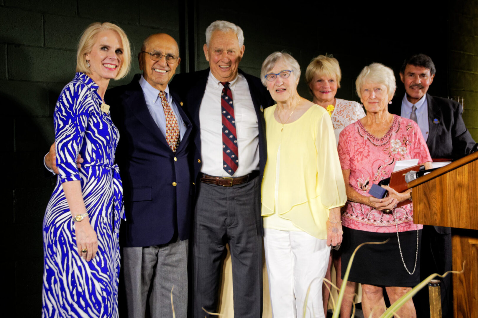 A group of people standing together in front of a wall.