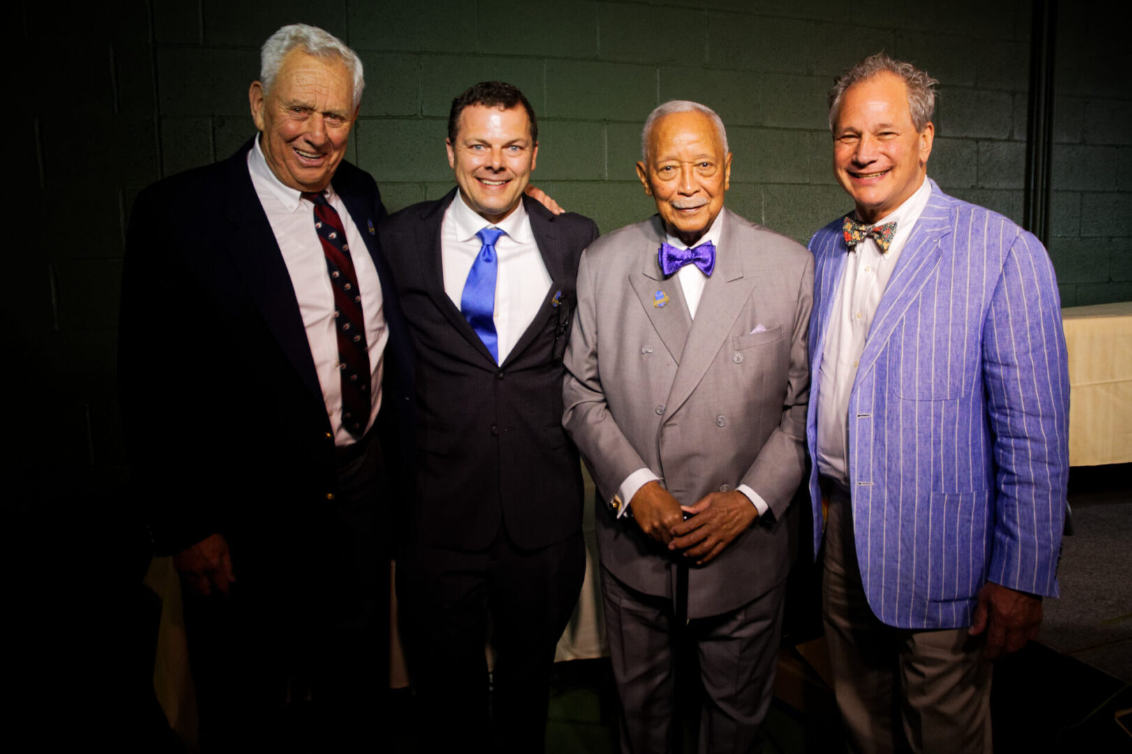 Four men in suits and ties standing next to each other.