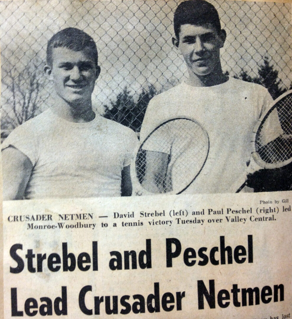 Two men holding tennis rackets in front of a fence.